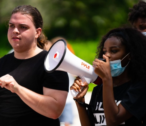 Black student activists — Joy, holding the megaphone, and Olivia, behind her — participate in a Black Lives Matter protest in Weston in June. The 17-year-olds are among the young people pushing to get police out of schools in South Florida. WLRN is not using their last names because they've received online threats