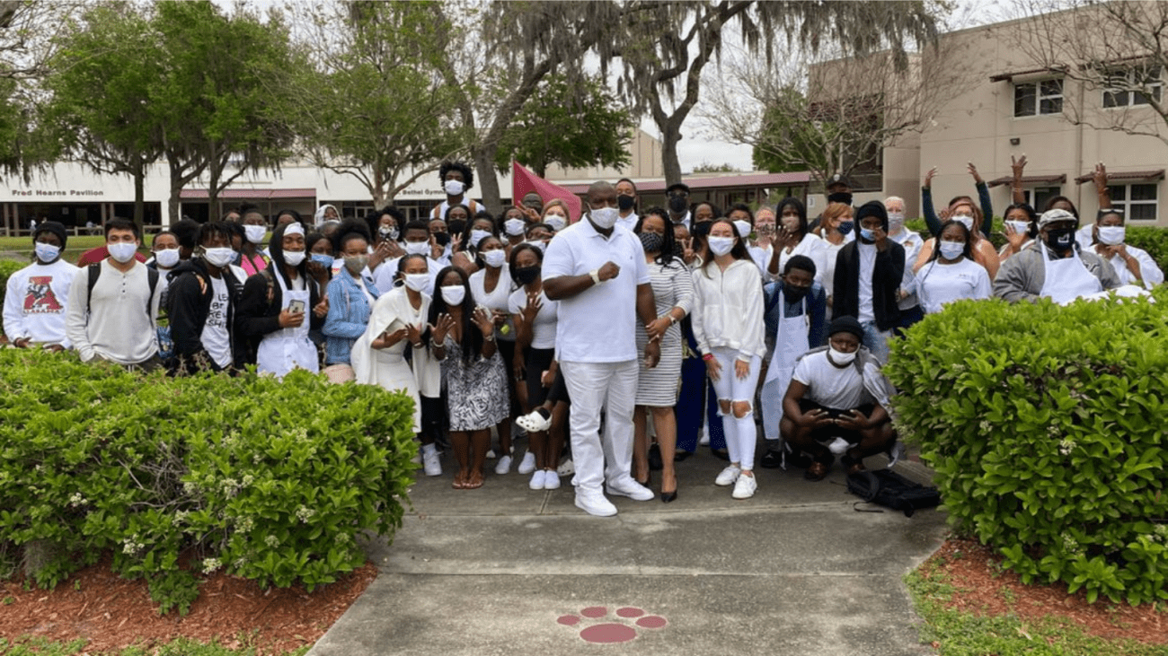 Delvin White, center, stands with students and staff at Middleton High School on Monday, wearing white to show their support for the fired Tampa police officer as he tries to get his job back. White, who was a school resource officer at Middleton, was fired for using a racial slur on two occasions.