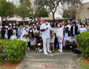 Delvin White, center, stands with students and staff at Middleton High School on Monday, wearing white to show their support for the fired Tampa police officer as he tries to get his job back. White, who was a school resource officer at Middleton, was fired for using a racial slur on two occasions.