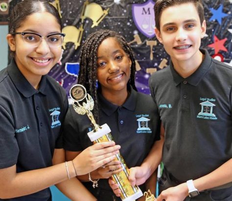 Jocelyn Hernandez, Gabriella Vega and Maurits Acosta hold one of the awards they won for an environmental project, on June 9, 2021. They are Miami Lakes Middle School students who proposed flood prevention legislation to the town council after Tropical Storm Eta flooded parts of the west Miami-Dade town, including their school auditorium